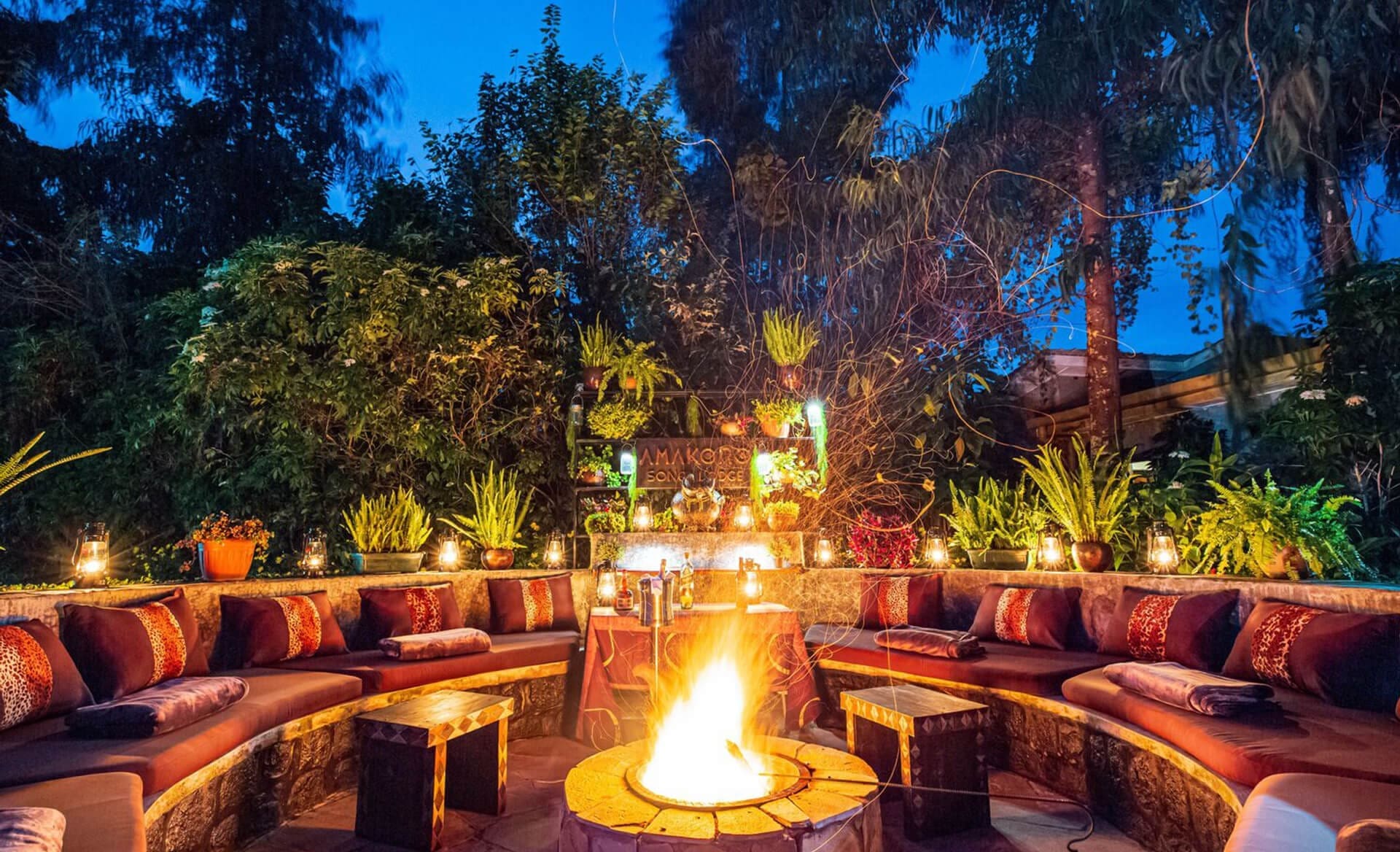 An intimate outdoor circular seating area with a central fire pit at dusk.