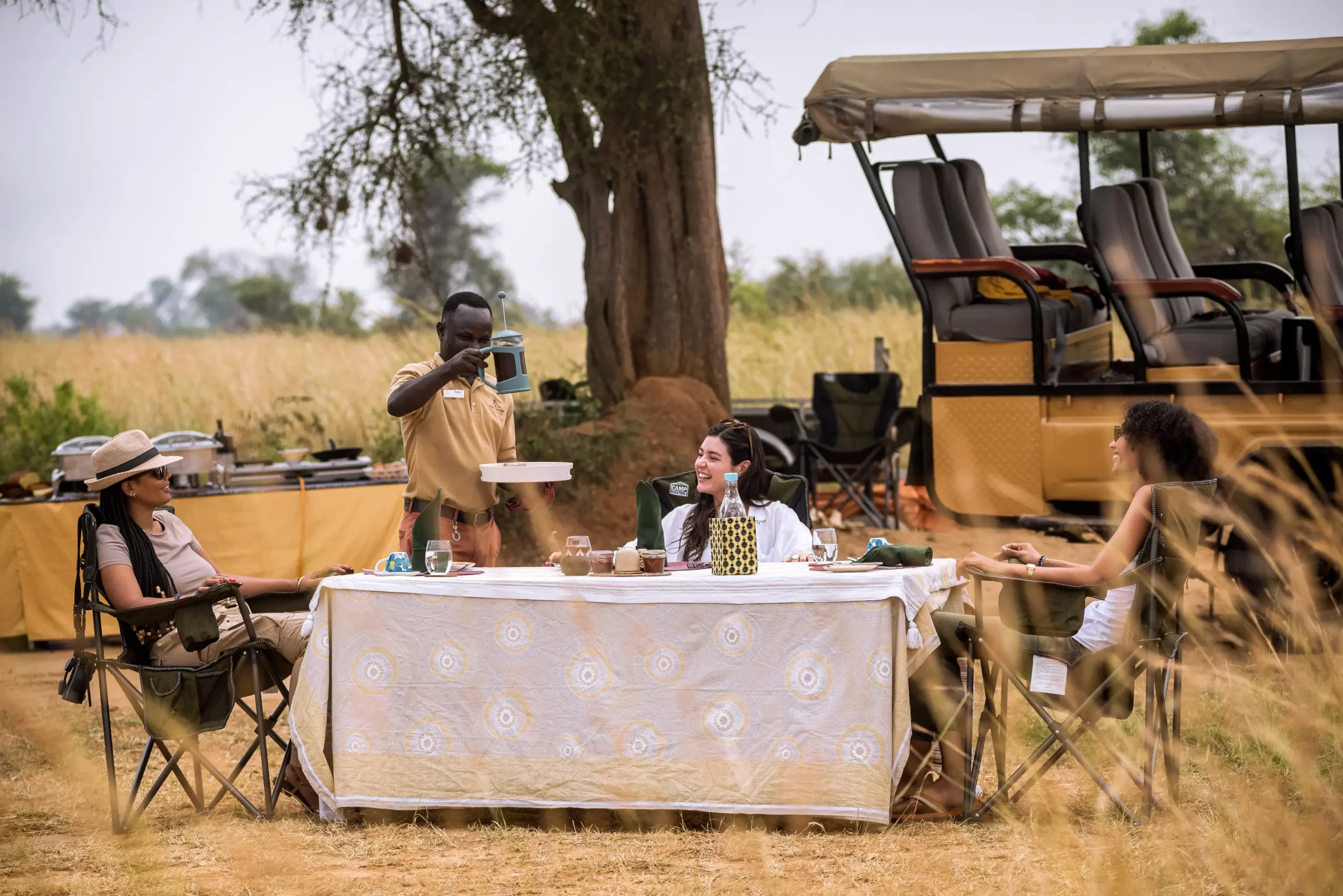 Best Uganda Luxury Holidays 2026/2027: Ultimate Safari Guide 45 Travelers enjoying a private bush meal beside a luxury safari vehicle during a Uganda luxury holiday