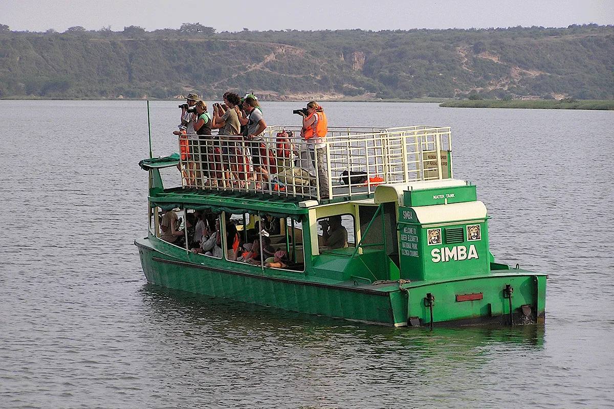 Rwanda vs Uganda Safari: Which Is Best? 2026/2027 11 Travelers using binoculars and cameras from a safari boat during a water-based wildlife viewing experience in East Africa