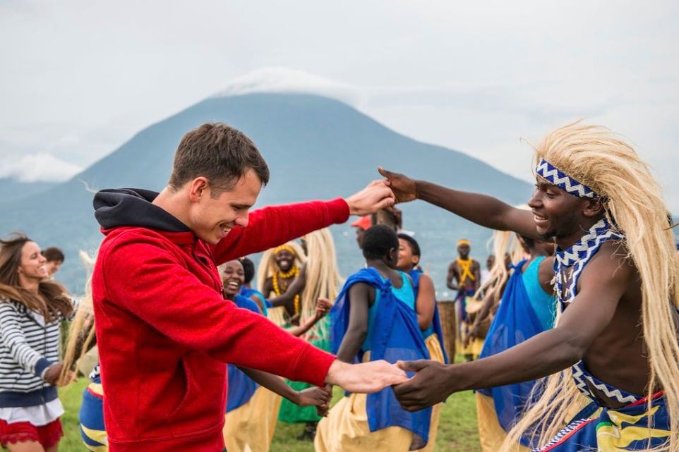 Rwanda vs Uganda Safari: Which Is Best? 2026/2027 33 Traveler joining traditional Rwandan dancers during a cultural experience with scenic volcanic mountains in the background