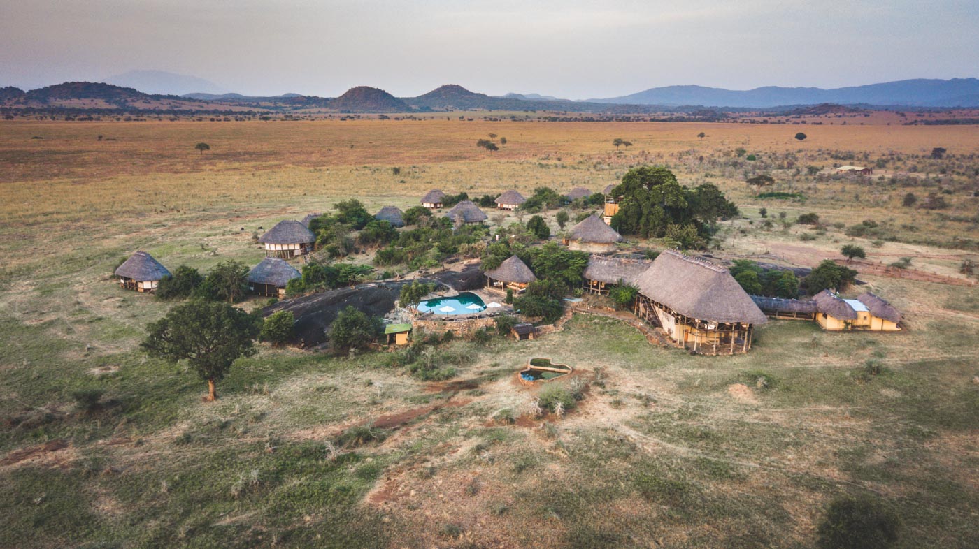 Best Uganda Luxury Holidays 2026/2027: Ultimate Safari Guide 31 Aerial view of a luxury wilderness lodge with thatched cottages and a swimming pool surrounded by the open savannah of Kidepo Valley National Park in Uganda