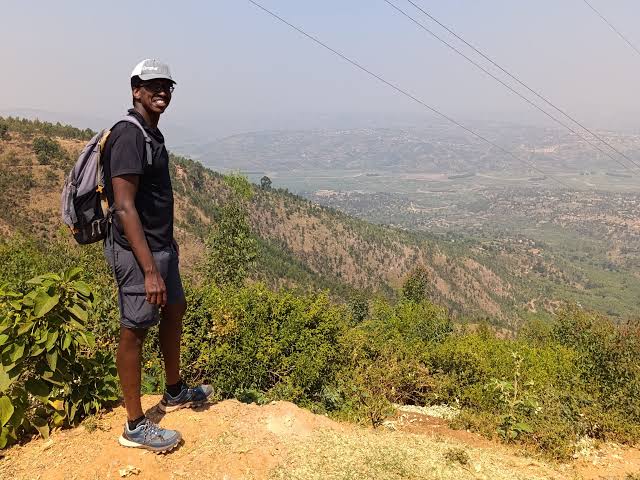 kigali city tour 21 A hiker enjoying panoramic views from Mount Kigali overlooking the city and surrounding hills in Kigali, Rwanda.
