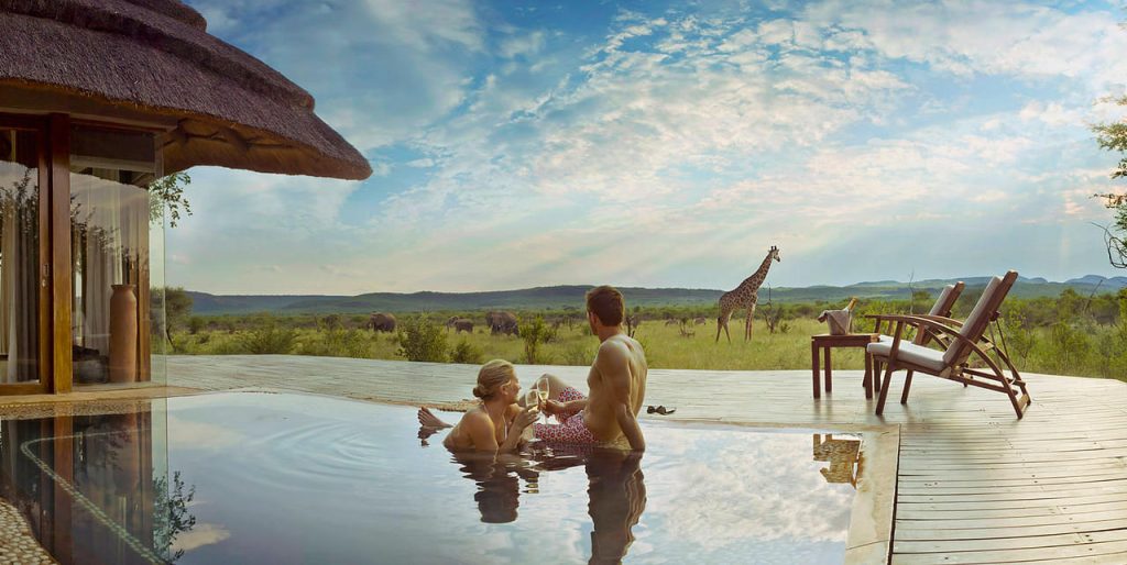Rwanda Honeymoon Safari 11 Couple relaxing in an infinity pool at a luxury safari lodge overlooking Rwanda's wildlife during a romantic honeymoon safari.