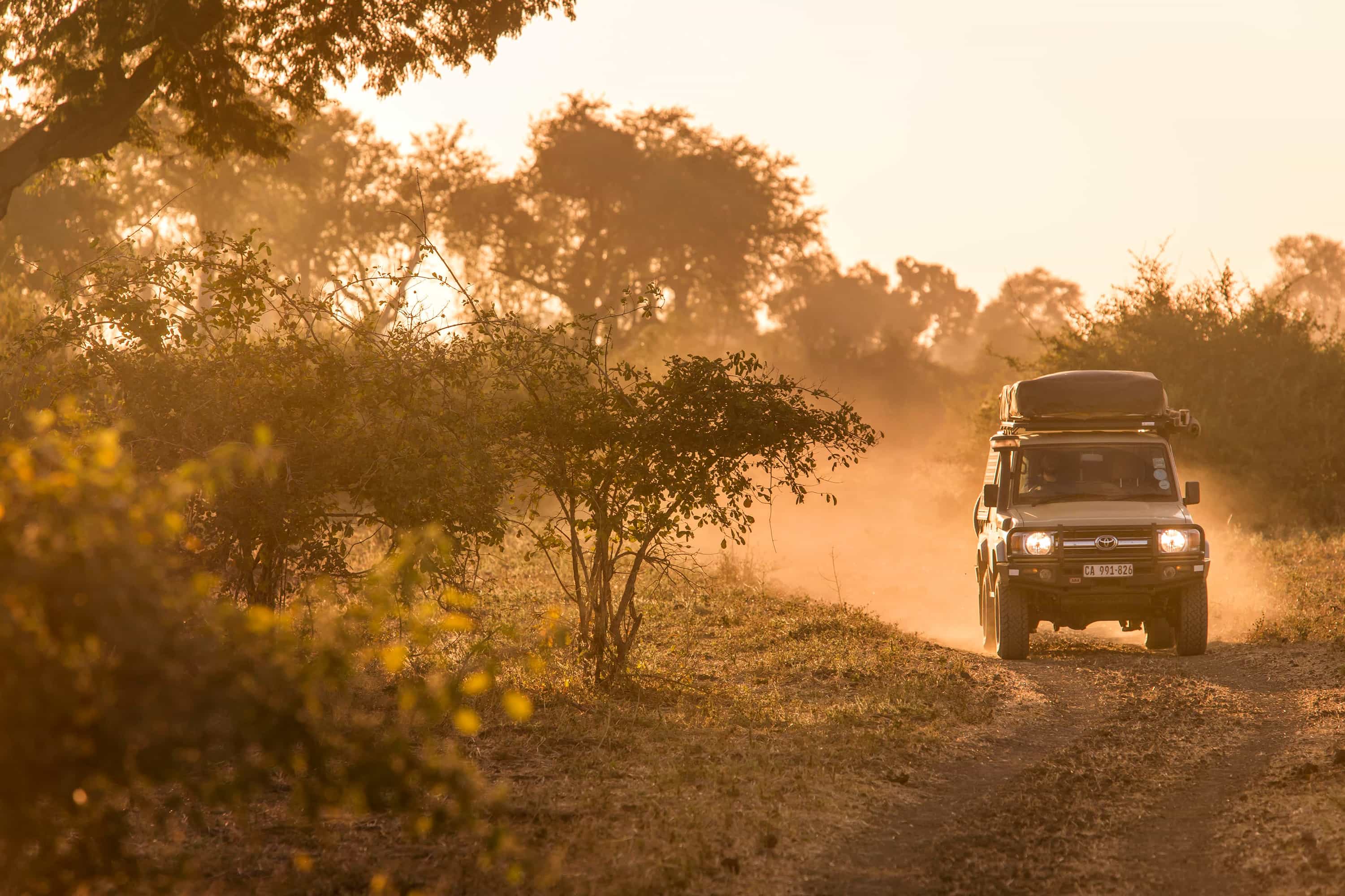 Nkuringo Gorilla Trekking Guide 19 A 4x4 safari land cruiser driving on a winding dirt road surrounded by forest