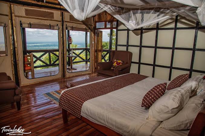 Queen Elizabeth National Park Guide 39 A rustic lodge bedroom with a large bed and panoramic park views.