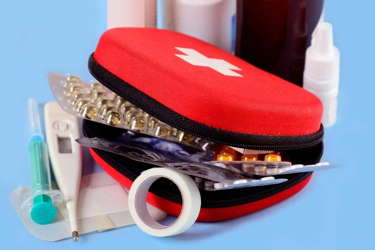 Uganda Safety Guide 9 A red first aid pouch with a white cross, thermometer, syringe, and pills.