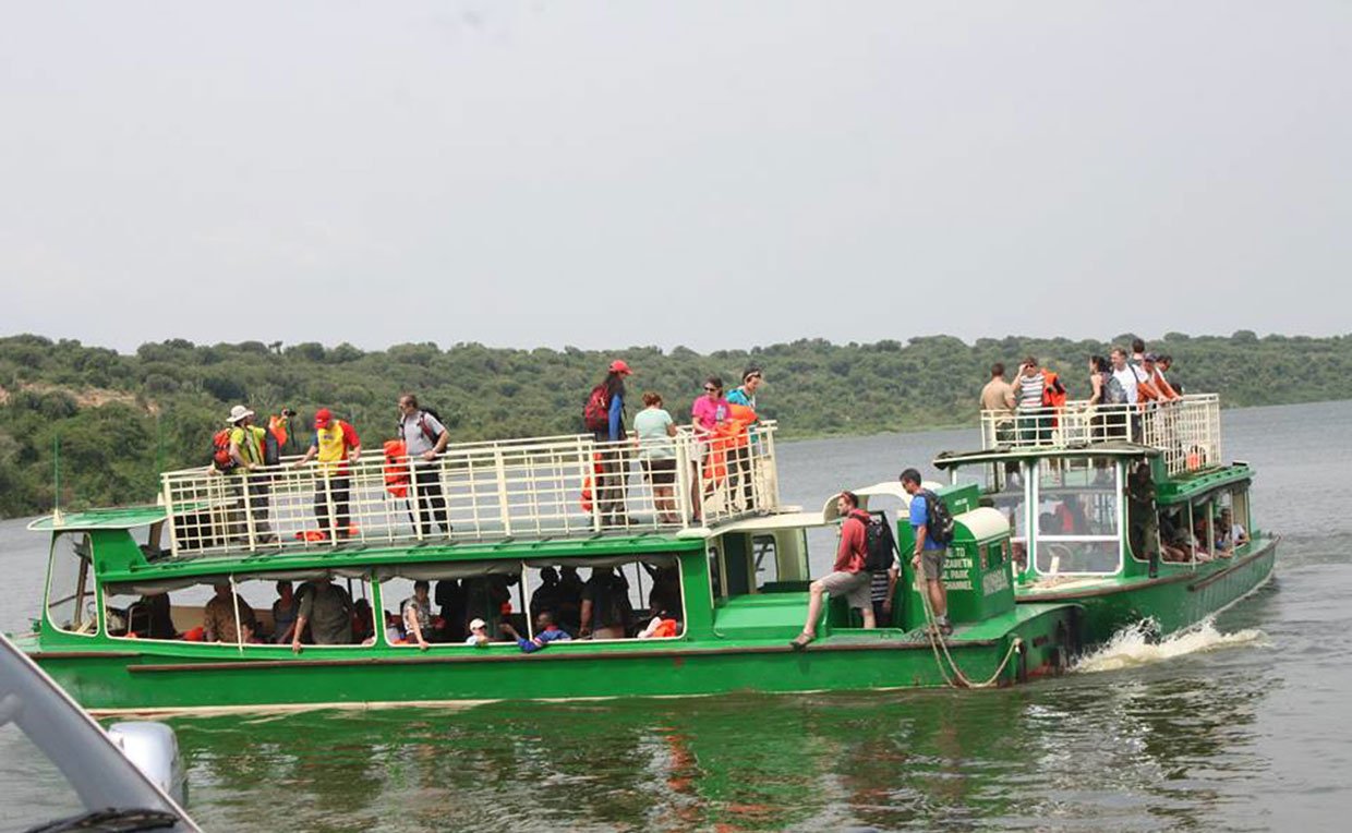 Queen Elizabeth National Park Guide 29 Tourists ride a green double-decker safari boat on a river in Uganda.