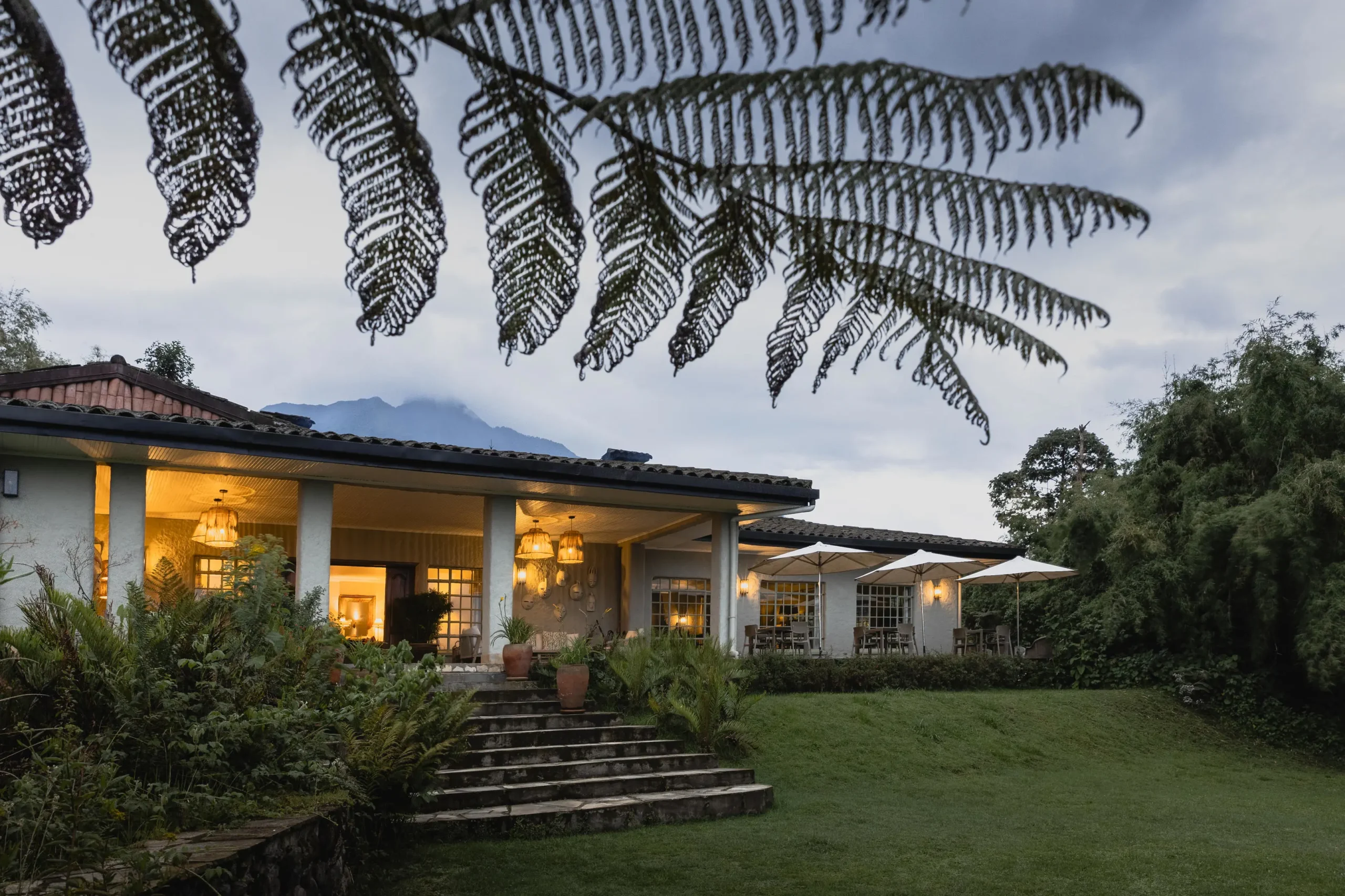 Luxury stone lodge with steps leading to a green lawn near misty mountains